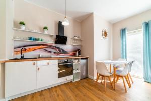 a kitchen with white cabinets and a table with chairs at Komfortowy Apartament w Karpaczu do 5 os. in Karpacz