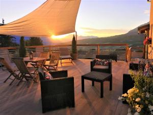 une terrasse avec des chaises et des tables et un coucher de soleil dans l'établissement Gîtes Les Garianes, à Saint-Léger-les-Mélèzes