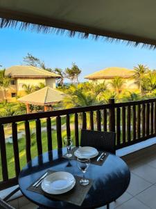 een tafel met borden en wijnglazen op een balkon bij VG Sun Cumbuco Bangalô Vista Mar in Cumbuco