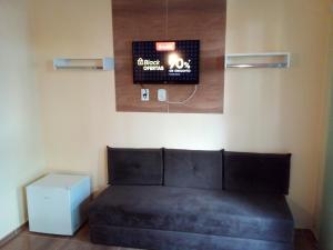 a bed in a room with a clock on the wall at Suíte do Galo in Arraial do Cabo