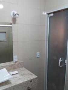a bathroom with a shower and a sink and a mirror at Suíte do Galo in Arraial do Cabo