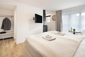 a white bedroom with two towels on a bed at EH Apartments Mars in St. Gallen