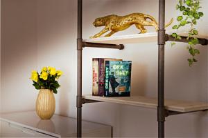 een plank met een boek en een vaas met bloemen bij EH Apartments Mars in St. Gallen