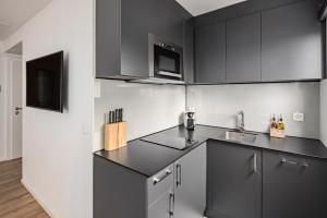 a kitchen with black and white cabinets and a sink at EH Apartments Mars in St. Gallen