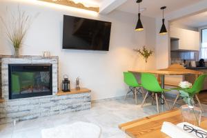 a living room with a fireplace and a table with green chairs at Apartamenty DOMKI GIEWONT in Zakopane