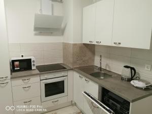 a kitchen with white cabinets and a sink and a microwave at CITY CENTER PEARL #new#free reserved parking in garage elevator direct access#business and pleasure#city view&balcony&sunny&cafes&markets&tram#city center in Zagreb