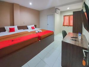 a hotel room with a large bed and a desk at RedDoorz Plus at Pelita Guest House Balikpapan in Balikpapan