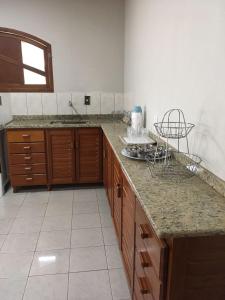 uma cozinha com um balcão de granito e armários de madeira em Passarinhada Hospedagem em Domingos Martins