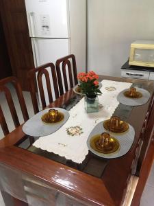 una mesa de madera con cuatro platos y flores. en Passarinhada Hospedagem en Domingos Martins
