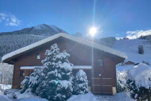 a house with a snow covered tree in front of it at La Joly - ChaletYap in La Chapelle-dʼAbondance