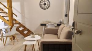 a living room with a couch and a clock on the wall at Uni Island - City Center Suites in Heraklio Town