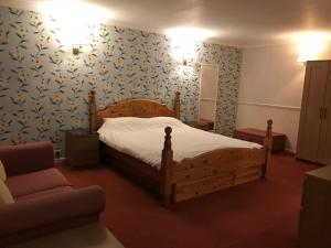 a bedroom with a wooden bed and a chair at The Highfield Hotel in Bradford