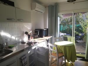 eine Küche mit einem Waschbecken und einem Tisch sowie einem Tisch und Stühlen in der Unterkunft Rez de jardin cosy avec terrasse fleurie in Arles-sur-Tech