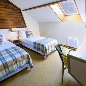 a hotel room with two beds and a skylight at Hôtel Le Savoie in Albertville