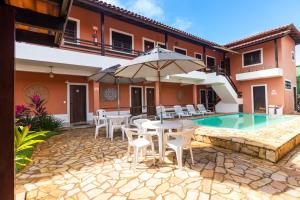 eine Terrasse mit einem Tisch, Stühlen und einem Pool in der Unterkunft HOTELARE Pousada Bóra Morá in Ubatuba