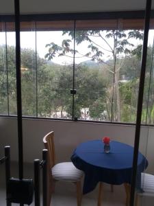 une table bleue et des chaises dans une chambre avec fenêtre dans l'établissement Pousada Aromas da Pedra, à Pedra Azul