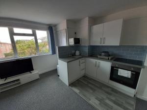 a kitchen with white cabinets and a flat screen tv at 45 New Esplanade Court in Paignton