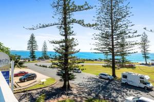 a car parked on the side of a road next to a beach at Beach House Holiday Apartments in Port Macquarie