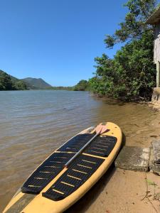 a paddle board sitting on the shore of a river at Recanto Nativos in Garopaba