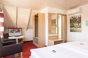 a bedroom with a bed and a desk with a computer at Hotel-Restaurant Straussen in Harburg