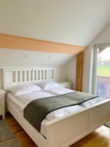 a large white bed in a bedroom with a window at Avio rooms in Cerklje na Gorenjskem