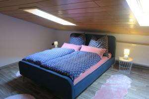 Un dormitorio con una cama azul con almohadas rosas y azules en Ferienwohnung Fröhlich en Dorfprozelten