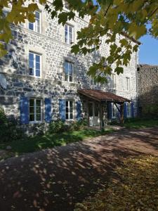 un antiguo edificio de piedra con toldo delante de él en Chambres et table d'hôtes Régord'âne, en Le Brignon