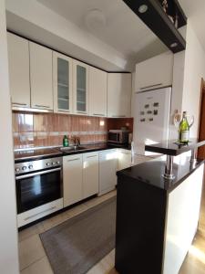 een keuken met witte kasten en een zwart aanrecht bij Apartman Ana in Bosanska Gradiška