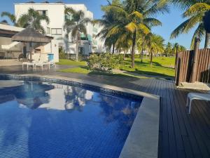 a swimming pool in front of a house with palm trees at Cond Mediterrâneo I - Iberostate in Praia do Forte