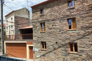ein Steingebäude mit einer Holztür und einem Balkon in der Unterkunft Casa Resineiro com Garagem e Terraço in Proença-a-Nova