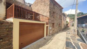 a house with a wooden garage door on a street at Casa Resineiro com Garagem e Terraço in Proença-a-Nova