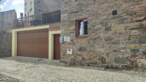a brick building with a garage door and a balcony at Casa Resineiro com Garagem e Terraço in Proença-a-Nova