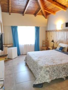 um quarto com uma cama grande e uma janela grande em Hostal El Korú em San Carlos de Bariloche
