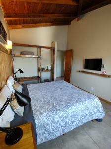 a bedroom with a bed with a blue comforter and a television at Hostal El Korú in San Carlos de Bariloche