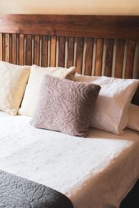 a bed with white pillows and a wooden headboard at Casa rural El Hornillo in Vallehermoso