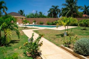 un jardín con piscina y palmeras en Ubuntu De La Villa- Palm View Estate en Mammee Bay