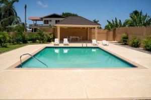 曼米湾Ubuntu De La Villa- Palm View Estate的一个带两把椅子和一张桌子的游泳池以及一间房屋