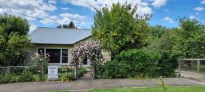 a house with a fence and flowers in front of it at Cottage on Main in Buchan