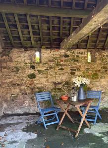 - deux chaises bleues et une table en bois devant un mur en pierre dans l'établissement 1-Bed luxury studio Apartment Cockermouth, à Cockermouth