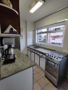een keuken met een fornuis, een wastafel en een raam bij Apartamento em Caioba com wi-fi in Matinhos