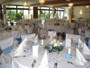 Cette grande chambre comprend des tables blanches avec des fleurs blanches et des bougies. dans l'établissement Eichenhof Hotel GbR, à Eislingen/Fils
