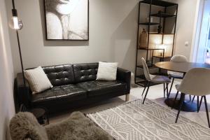 a living room with a black leather couch and a table at 3 Room Luxury Design Apartment with Airconditioning, Close to Gent St-Pieters Station in Ghent