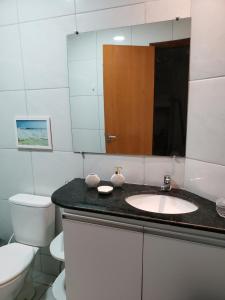 a bathroom with a sink and a toilet and a mirror at Chaleville Coqueiro 1001 in Luis Correia