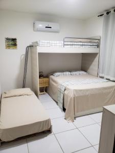 two beds in a room with white tile floors at Chaleville Coqueiro 1001 in Luis Correia