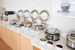 a kitchen counter with many pans of food on it at Hotel S-Plus Hiroshima Peace Park in Hiroshima