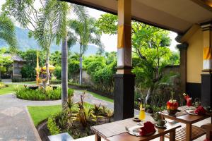 a patio with tables and a view of a garden at Taruna Boutique Homestay & Spa in Pemuteran