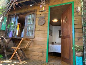 a wooden house with a door and a chair at Chale canto verde Villa Facioni in Palhoça +15 photos