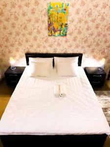 1 dormitorio con 1 cama blanca y 2 mesitas de noche en Трехкомнатные апартаменты в центре Левого Берега г.Нур-султан en Astaná