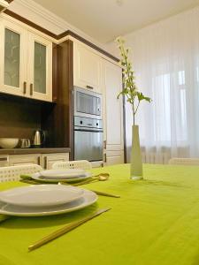 una cocina con una mesa verde con platos y palillos chinos en Трехкомнатные апартаменты в центре Левого Берега г.Нур-султан en Astaná