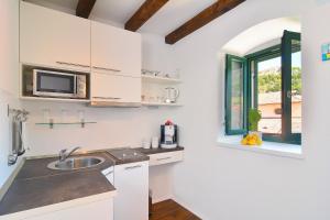 a white kitchen with a sink and a window at Apartments and Rooms Kampanel in Hvar